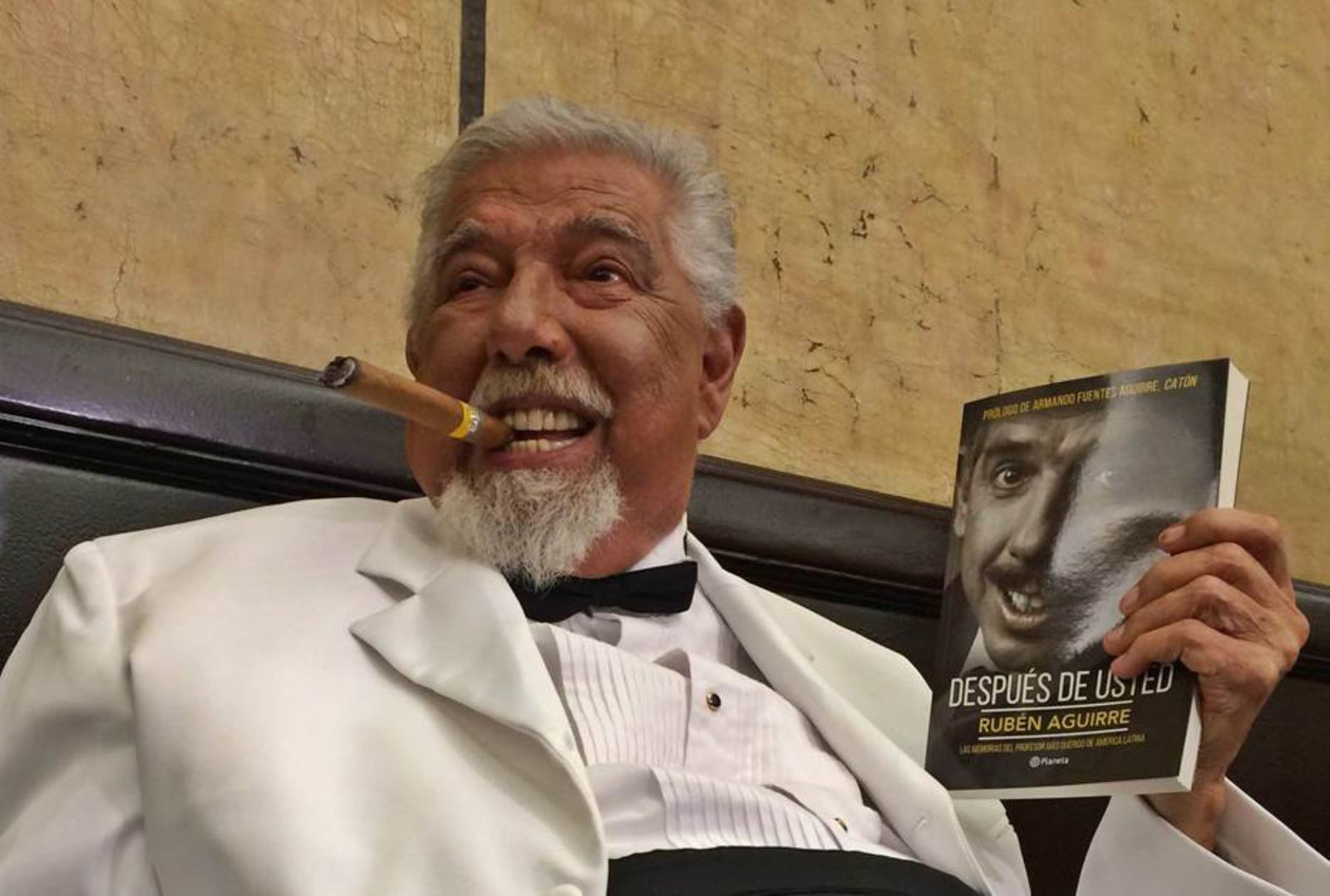 Hombre mayor con cigarro y libro en mano.