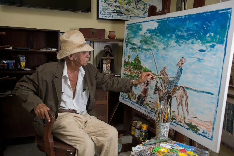 Artista pintando cuadro en estudio.