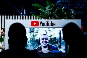 Visitantes junto a una pantalla con el logotipo de YouTube, en una fotografía de archivo. EFE/EPA/FILIP SINGER.